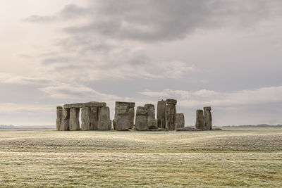 Built structure on field against cloudy sky