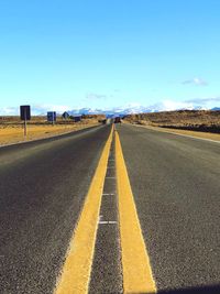 Surface level of empty road against clear blue sky