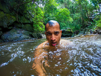 Portrait of young man in front of river in forest