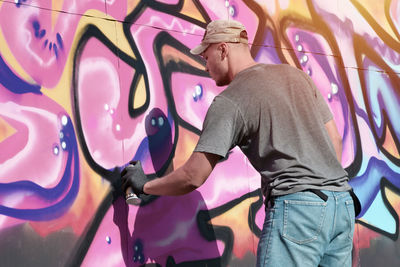 Side view of man standing against yellow wall