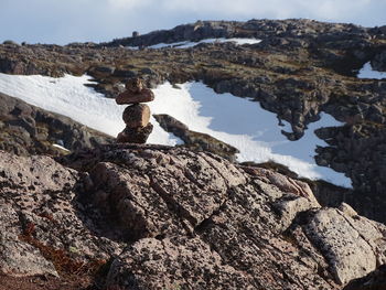 Stack of rocks by lake against sky