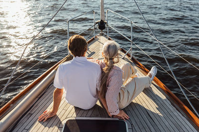 Rear view of women sitting on sailboat in sea