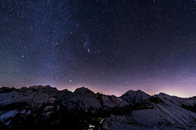 Scenic view of snowcapped mountains against sky at night