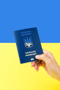 Cropped hand of woman holding paper against blue background