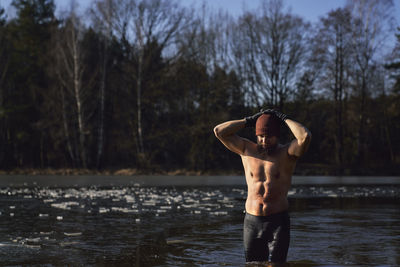 Shirtless man standing in river