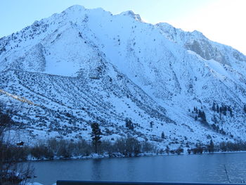 Scenic view of lake by snowcapped mountain against sky