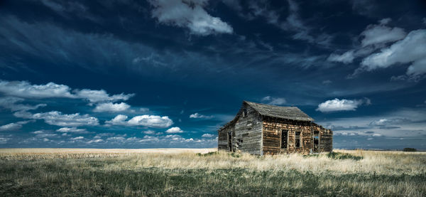 Abandoned building on field against sky