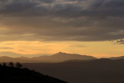 Scenic view of dramatic sky over mountains during sunset