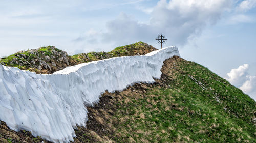 Low angle view of cross on mountain against sky