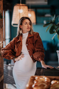 Portrait of pregnancy young woman standing in bakery 