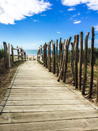 Boardwalk on beach against blue sky