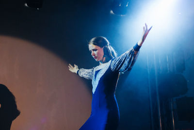 Woman with arms raised standing in music concert