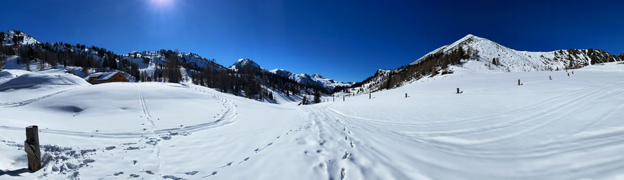 Panoramic view of snowcapped mountains against clear blue sky