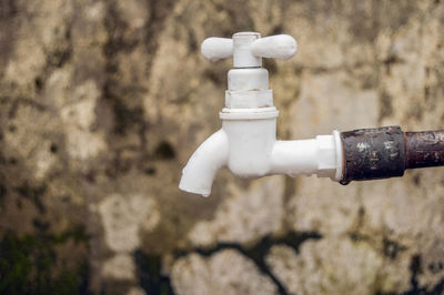 Close-up of white faucet against wall