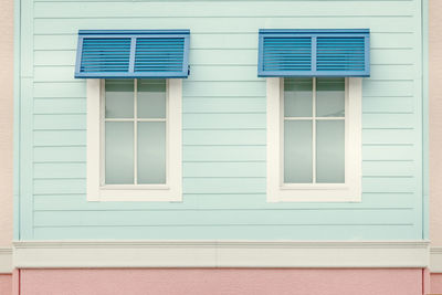 2 windows in a turquoise wooden wall