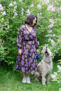 Rear view of woman with dog against purple flowering plants