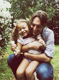 Portrait of happy mother holding baby sitting in park