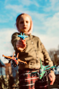 Low angle view of boy playing with airplanes against sky