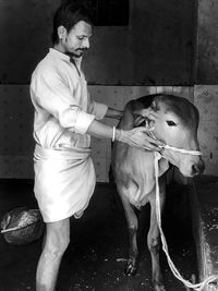 Man stroking cow at shed