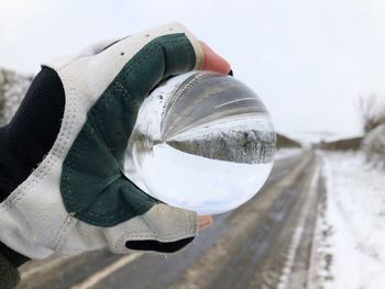Crystal ball in hand, looking down a country road with snow in winter. 