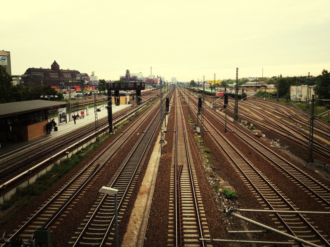 railroad track, rail transportation, transportation, public transportation, railroad station, railroad station platform, high angle view, built structure, diminishing perspective, architecture, the way forward, building exterior, railway track, vanishing point, train - vehicle, city, sky, travel, mode of transport, clear sky