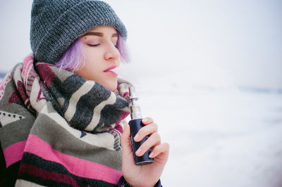 Close-up of girl holding ice while standing against sea