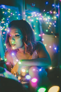 Portrait of woman looking at illuminated christmas lights