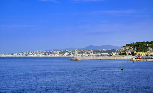 Scenic view of sea by buildings against blue sky