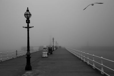 Street lights on bridge over sea against sky