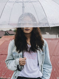 Midsection of woman with umbrella standing in rain