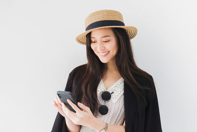 Smiling young woman using mobile phone against white background