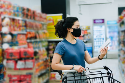 Full length of woman using mobile phone at store