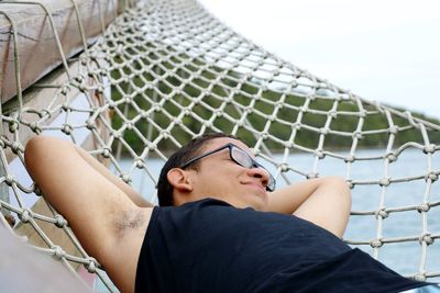 Close-up of man relaxing on hammock against sea