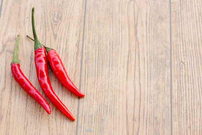 High angle view of red chili peppers on wooden table
