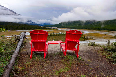 Empty chairs on land against sky