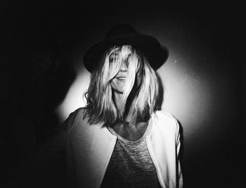 Close-up of woman wearing hat by wall in darkroom