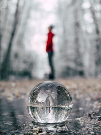 Reflection of man on crystal ball in forest