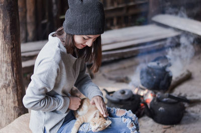 Woman stroking cat while sitting outdoors