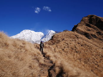 Man walking on mountain against clear blue sky