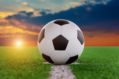 Digital composite of soccer ball on playing field against sky 