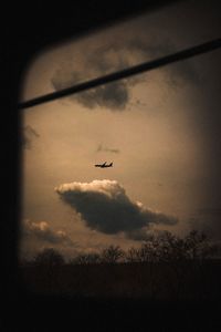 Low angle view of silhouette airplane flying against sky at sunset