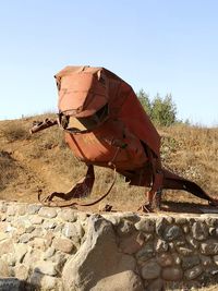 Man with umbrella on rock against clear sky
