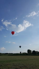 Hot air balloon flying over field against sky