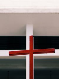 Close-up of red cross against building