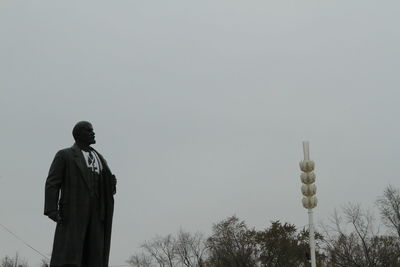 Rear view of man standing on cross against sky