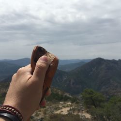 Close-up of hand holding mountain against sky