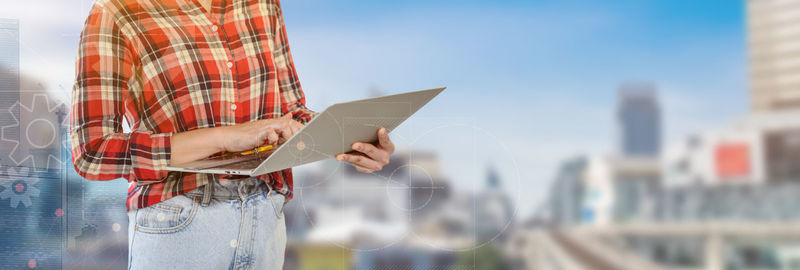 Midsection of man holding umbrella standing against sky
