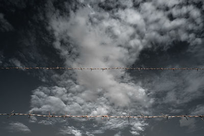 Low angle view of barbed wire against sky