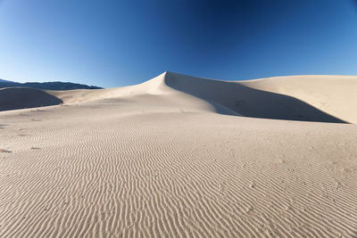 Sand dunes against clear blue sky