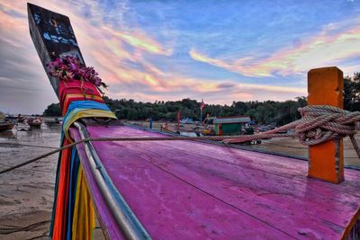 Multi colored boats moored on beach against sky during sunset